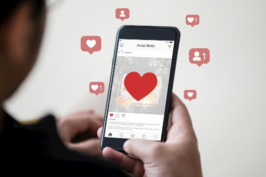 Homem rolando a tela do instagram no seu celular e recebendo curtidas em suas postagens
