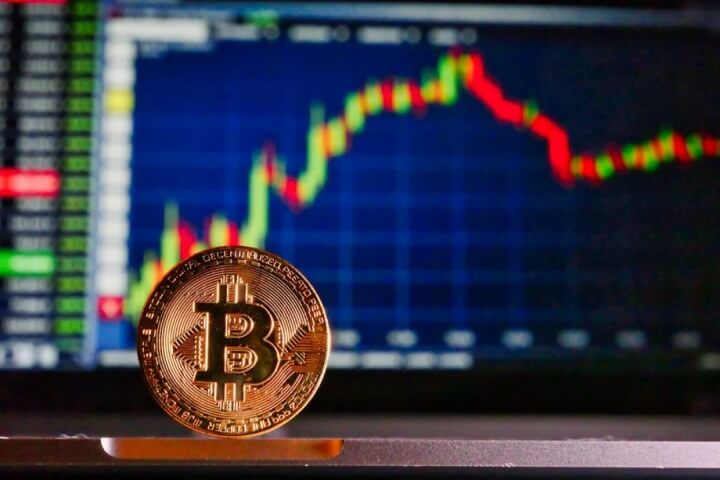 moeda bitcoin e ao fundo grafico trader de subida